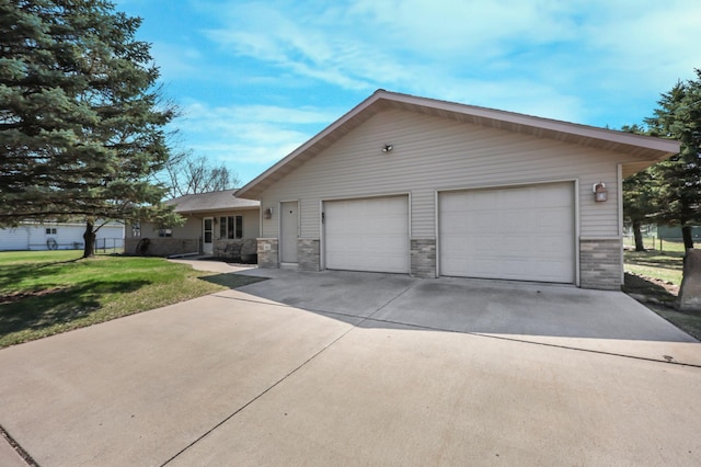 single story home featuring a detached garage, stone siding, a front yard, and fence