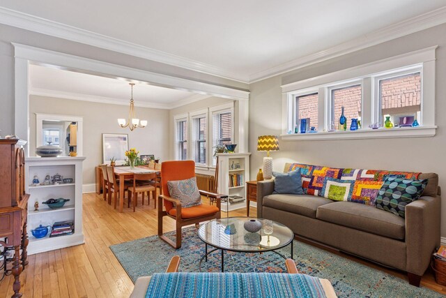 living area featuring wood-type flooring, crown molding, a notable chandelier, and baseboards