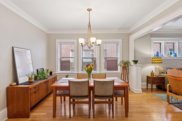 dining space featuring crown molding, baseboards, a notable chandelier, and light wood-style floors