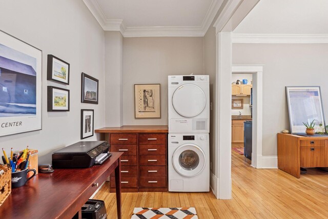 laundry area featuring light wood-style floors, crown molding, laundry area, and stacked washer / dryer