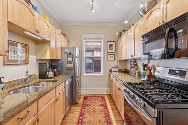 kitchen with a sink, appliances with stainless steel finishes, light brown cabinets, and light wood-style flooring
