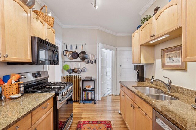 kitchen featuring light brown cabinetry, a sink, light wood-style floors, stone countertops, and stainless steel appliances