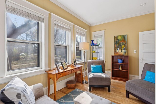 living area with crown molding, baseboards, and wood finished floors