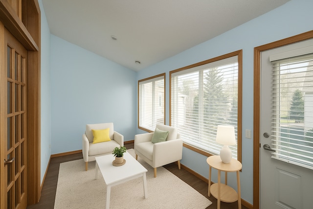 sitting room with dark wood finished floors, vaulted ceiling, and baseboards