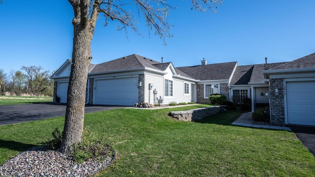 ranch-style home featuring a front lawn, an attached garage, driveway, brick siding, and a chimney