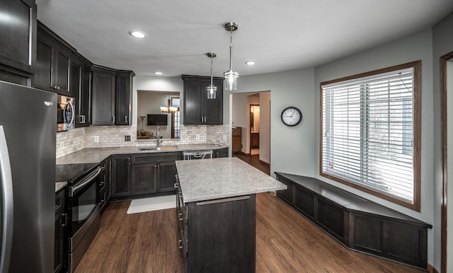 kitchen featuring stainless steel appliances, a sink, tasteful backsplash, a center island, and plenty of natural light
