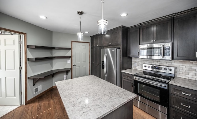 kitchen with stainless steel appliances, tasteful backsplash, a kitchen island, recessed lighting, and baseboards