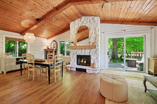 dining area featuring wooden ceiling, wood walls, light wood-style flooring, and a stone fireplace