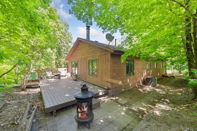 back of house with a fire pit, a deck, central AC unit, and a patio area