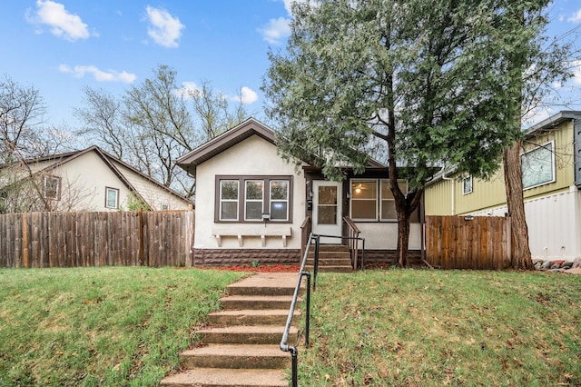 view of front of house featuring stucco siding, fence, a front yard, and entry steps
