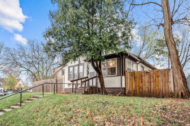 view of property exterior with stucco siding, fence, and a yard
