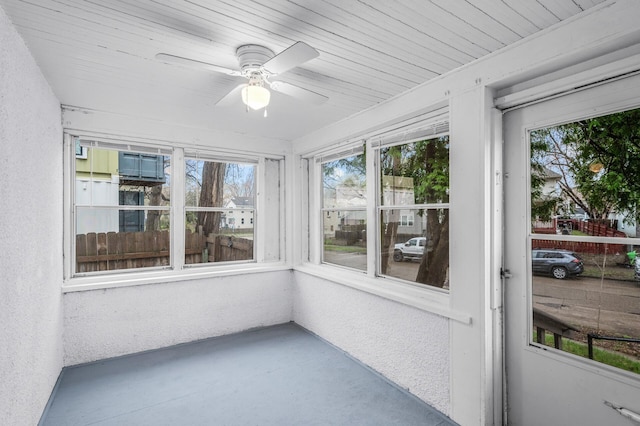 unfurnished sunroom with concrete floors, a textured wall, and a healthy amount of sunlight