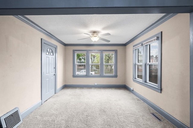 spare room featuring visible vents, carpet flooring, baseboards, and crown molding
