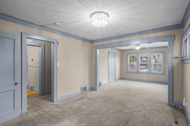 carpeted empty room with crown molding, a textured ceiling, and visible vents