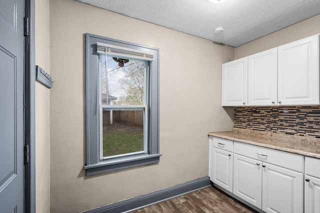 interior space with baseboards, backsplash, dark wood-style floors, and a textured ceiling