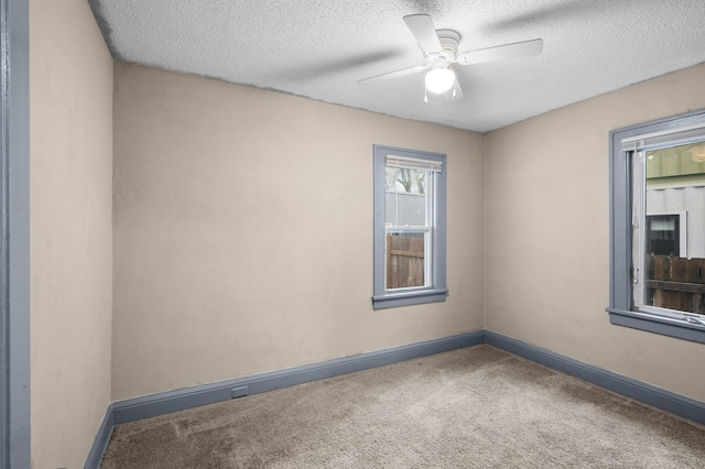 empty room featuring carpet floors, a ceiling fan, a textured ceiling, and baseboards