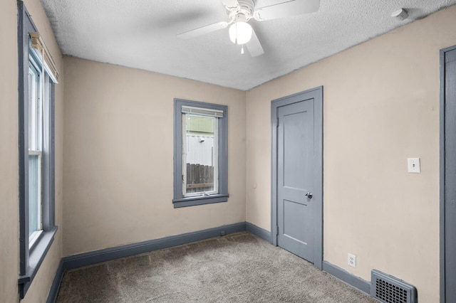 carpeted empty room with visible vents, baseboards, ceiling fan, and a healthy amount of sunlight