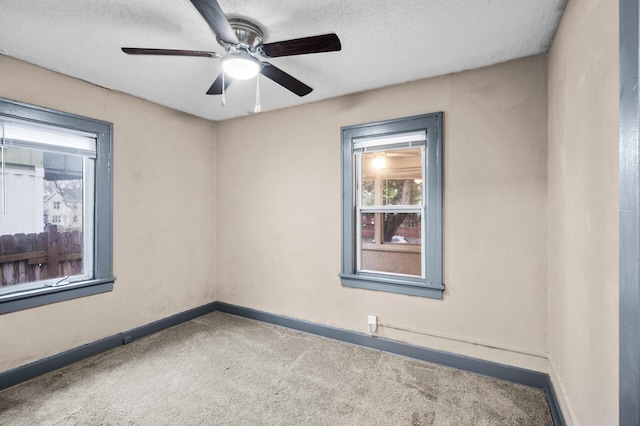 empty room with carpet floors, a ceiling fan, a textured ceiling, and baseboards