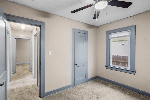 unfurnished bedroom with baseboards, carpet flooring, attic access, and a textured ceiling
