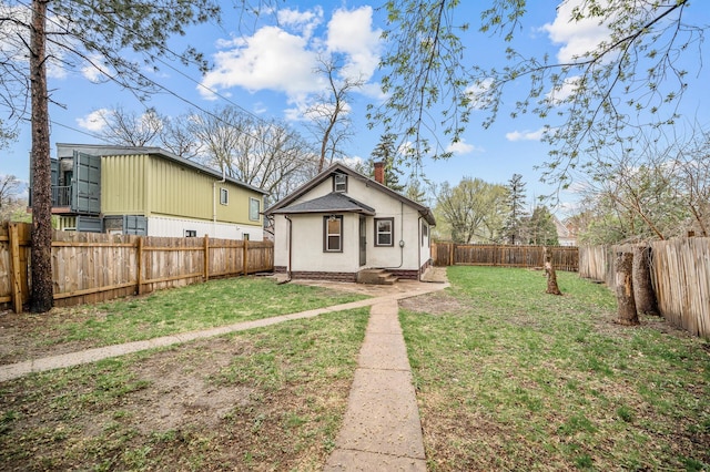 view of front of property with a fenced backyard, a chimney, stucco siding, and a front lawn