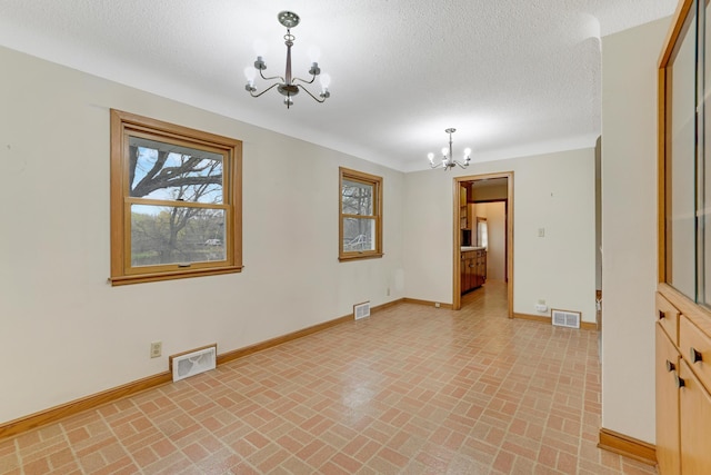 spare room featuring an inviting chandelier, brick floor, and visible vents