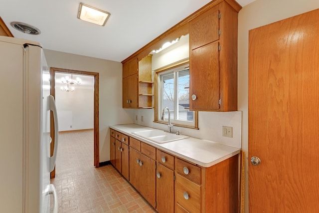 kitchen with visible vents, a sink, light countertops, freestanding refrigerator, and brick patterned floor