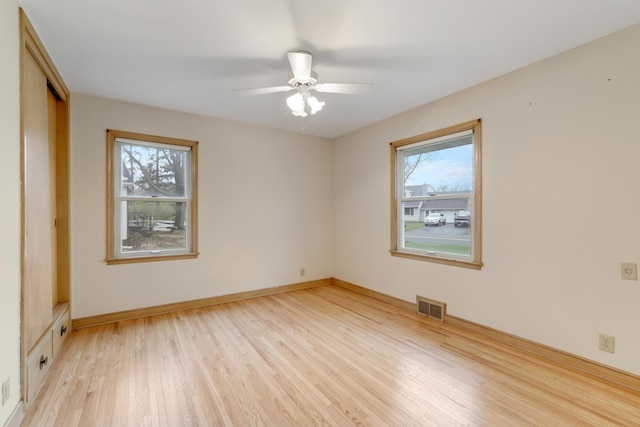 spare room featuring visible vents, plenty of natural light, ceiling fan, and light wood-type flooring