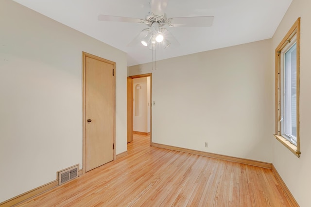 empty room with a ceiling fan, baseboards, visible vents, and light wood finished floors
