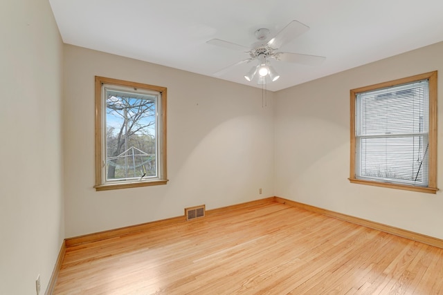 empty room with ceiling fan, baseboards, visible vents, and wood finished floors