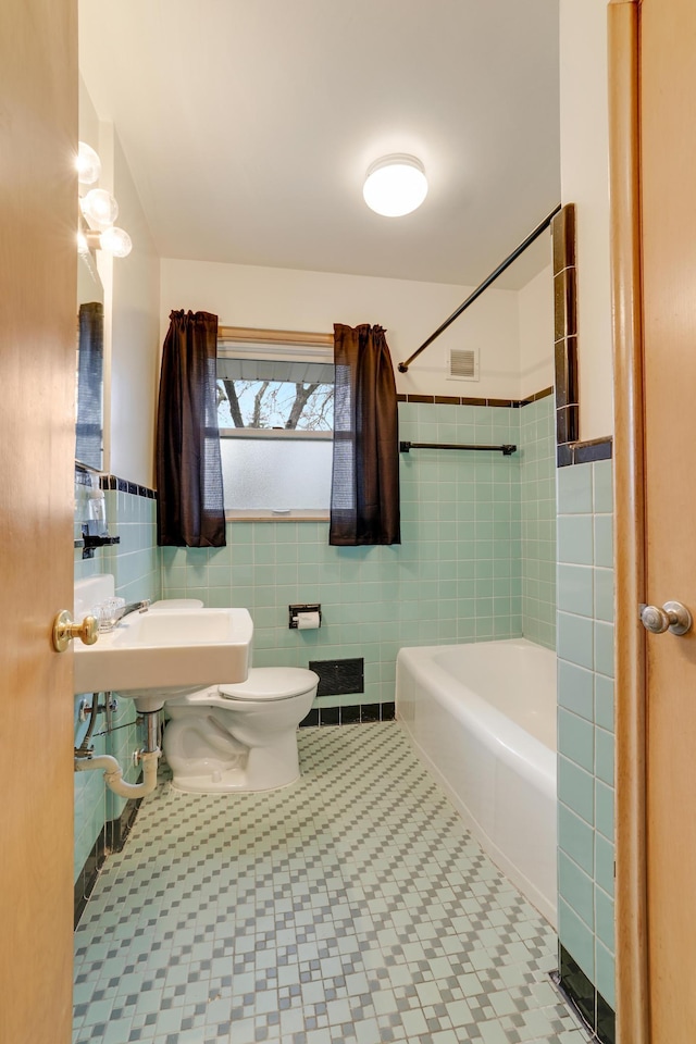 full bathroom featuring a sink, shower / bathtub combination, toilet, tile walls, and visible vents