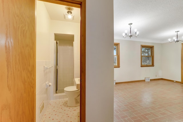 interior space with visible vents, a shower stall, brick patterned floor, and a notable chandelier
