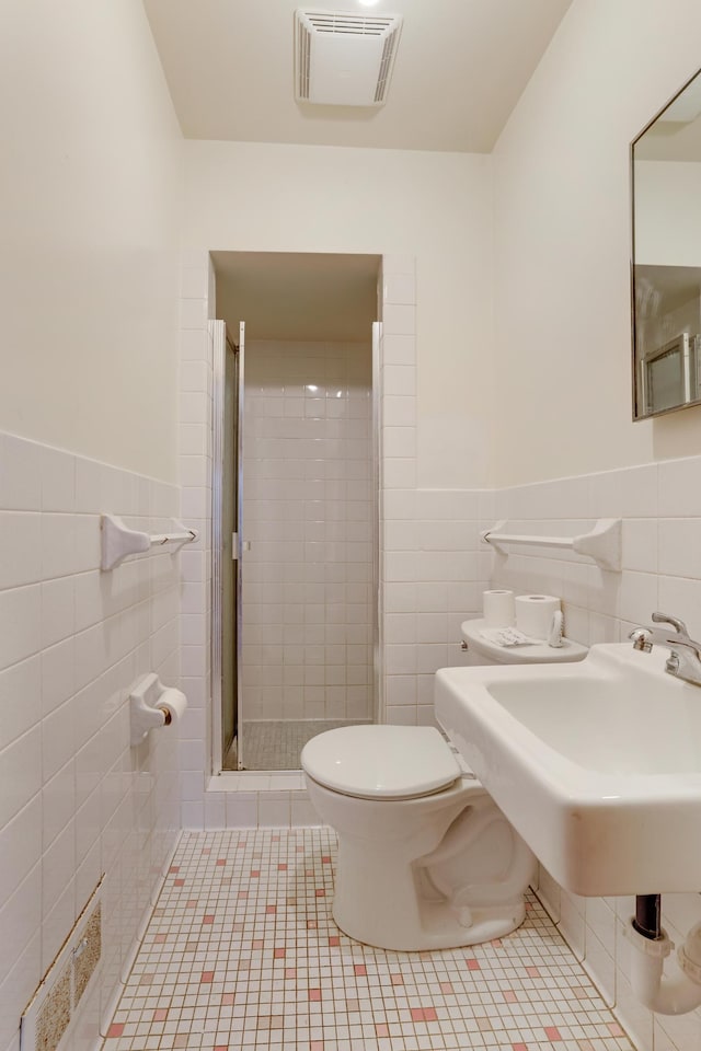 bathroom with visible vents, a shower stall, toilet, and tile walls