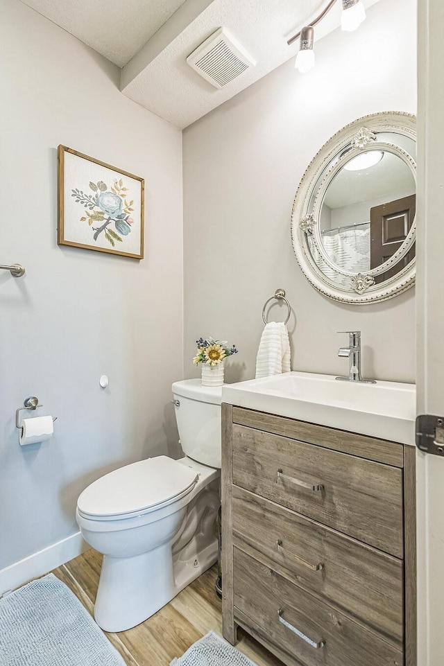 12720 Parkwood Dr, Burnsville, MN 55337 - bathroom with toilet, wood finished floors, vanity, and baseboards