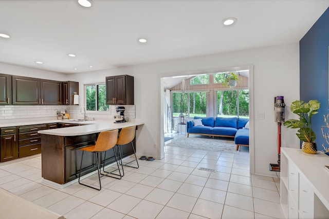 12720 Parkwood Dr, Burnsville, MN 55337 - kitchen with a breakfast bar, light countertops, backsplash, dark brown cabinets, and recessed lighting