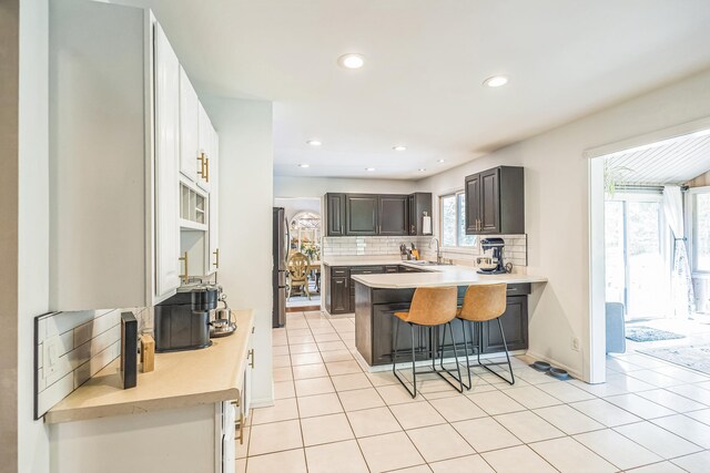 12720 Parkwood Dr, Burnsville, MN 55337 - kitchen with freestanding refrigerator, light countertops, decorative backsplash, a breakfast bar area, and recessed lighting