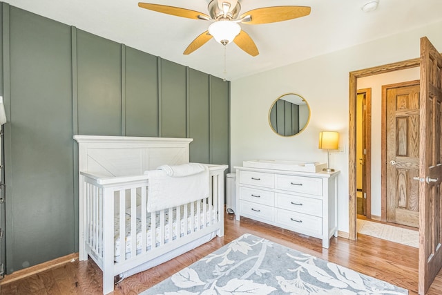 12720 Parkwood Dr, Burnsville, MN 55337 - bedroom featuring a nursery area, light wood-type flooring, a ceiling fan, and baseboards