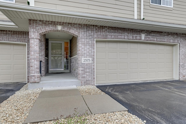 property entrance with brick siding and aphalt driveway