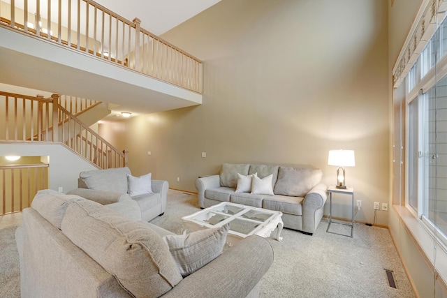 carpeted living room featuring baseboards, stairs, and a towering ceiling