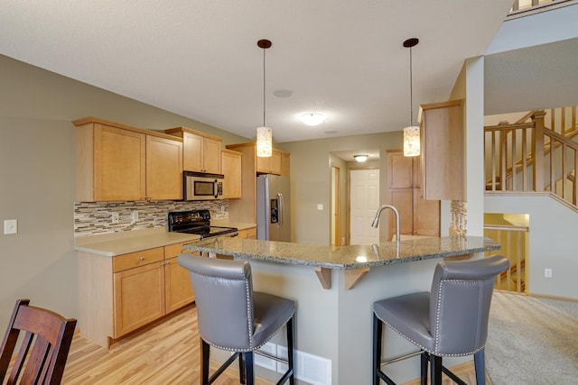 kitchen featuring light brown cabinetry, decorative backsplash, stainless steel appliances, and a peninsula