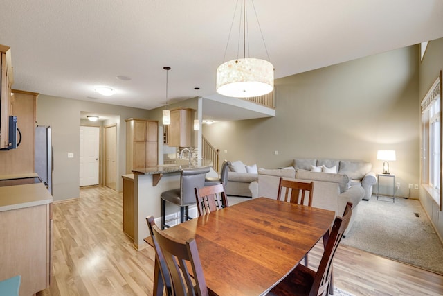 dining area featuring stairs, baseboards, and light wood-type flooring