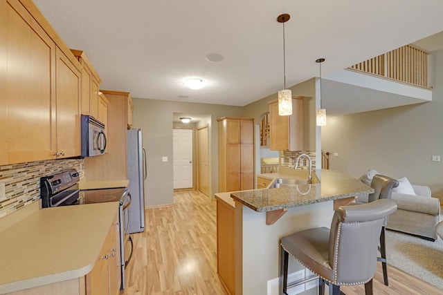 kitchen with freestanding refrigerator, range with electric stovetop, light wood-style floors, a sink, and backsplash