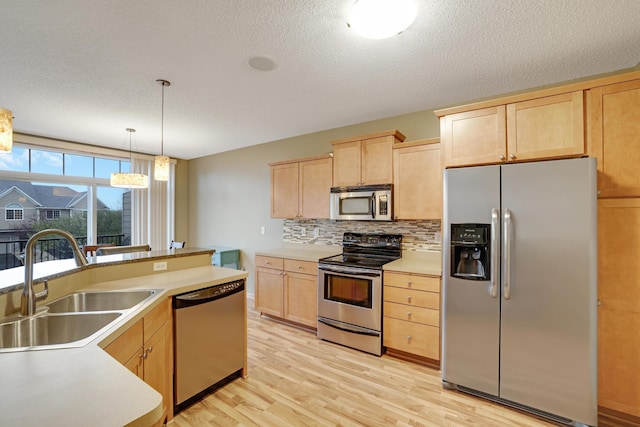 kitchen with a sink, light brown cabinets, stainless steel appliances, and light wood finished floors