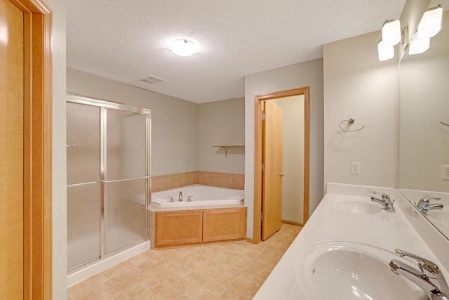 full bath with a textured ceiling, a sink, a garden tub, and a stall shower