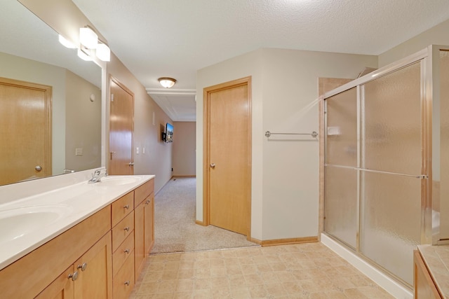 bathroom with a sink, baseboards, a shower stall, and double vanity