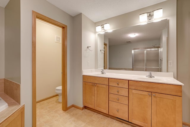bathroom with double vanity, a sink, toilet, and a shower stall