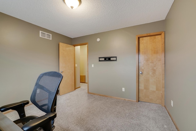 carpeted office featuring a textured ceiling, visible vents, and baseboards