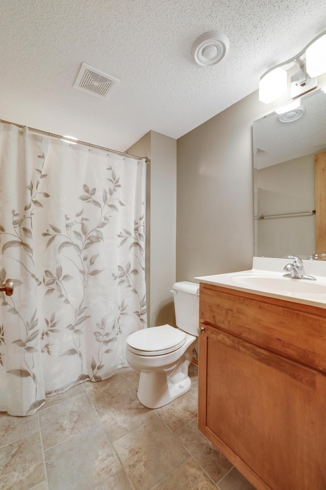 full bathroom featuring vanity, toilet, a textured ceiling, and visible vents