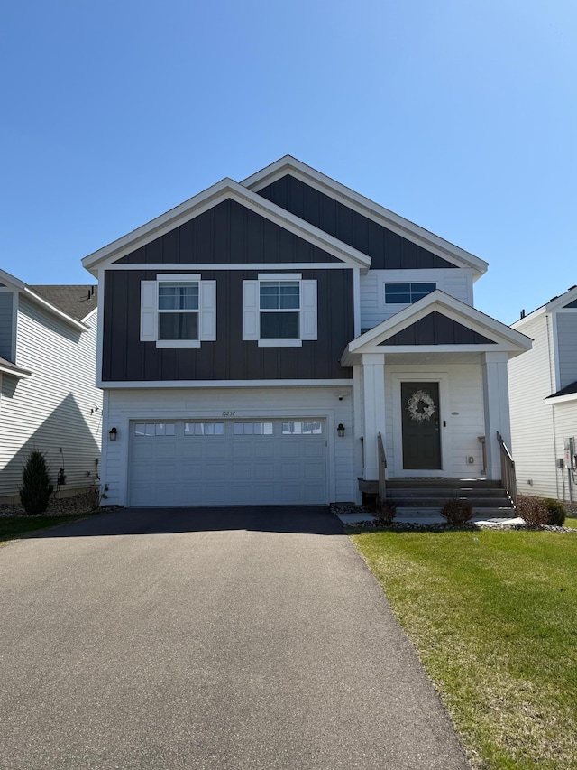 view of front of house featuring driveway, board and batten siding, a front yard, and an attached garage