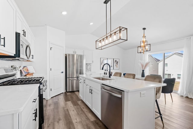 10257 Greenway Cir S, Cottage Grove, MN 55016 - kitchen with stainless steel appliances, a sink, a kitchen bar, a chandelier, and wood finished floors