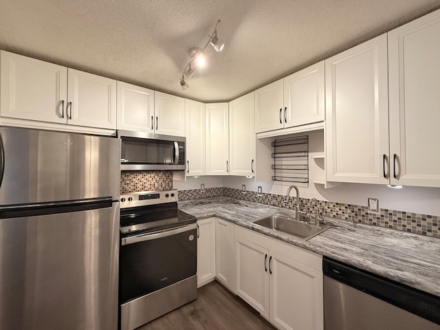 kitchen with stainless steel appliances, white cabinets, a sink, dark wood-style floors, and a textured ceiling